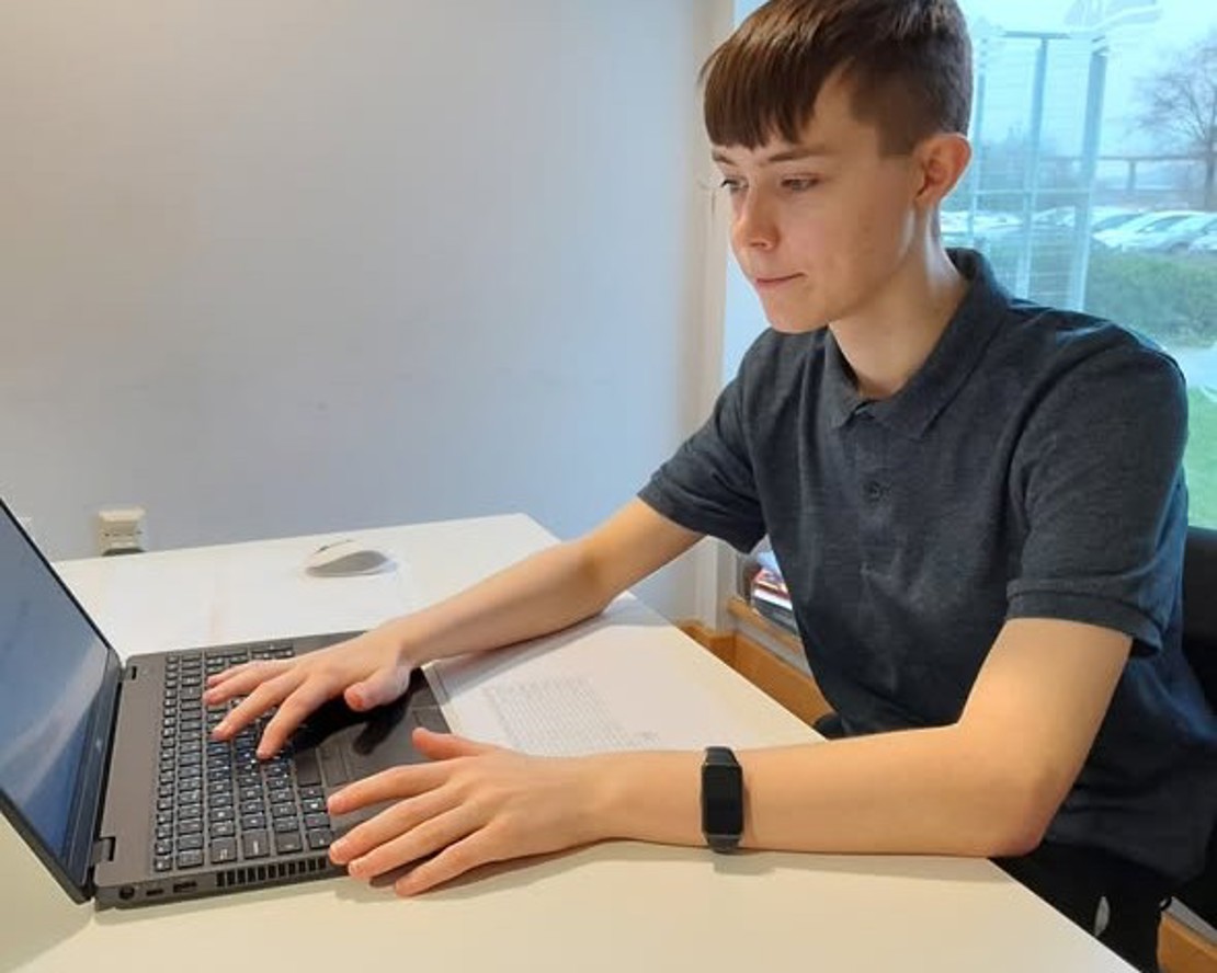 Griff working at his desk during his placement, focused on a task using his laptop